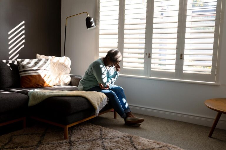 Woman sitting in quiet reflection in sunlit room, symbolizing emotional healing through grief counseling in Tulsa.